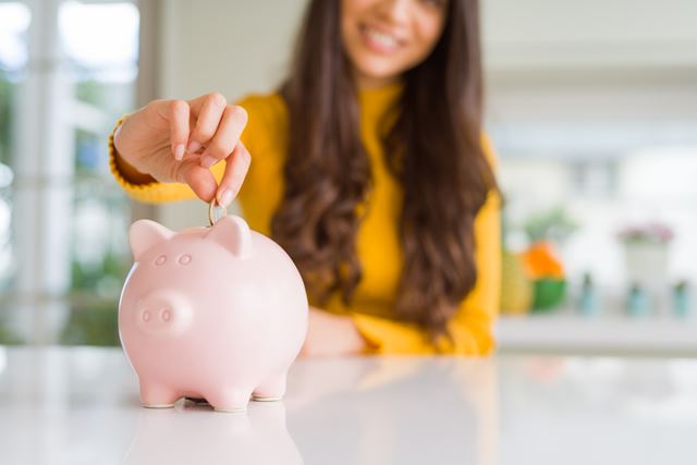 Kvinne som legger på mynt på en sparegris